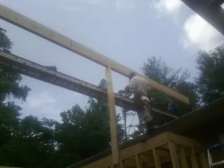 Carpenter setting a ridge beam over a new addition frame — Ice Dam Removal by Roofing Brothers in Firth
