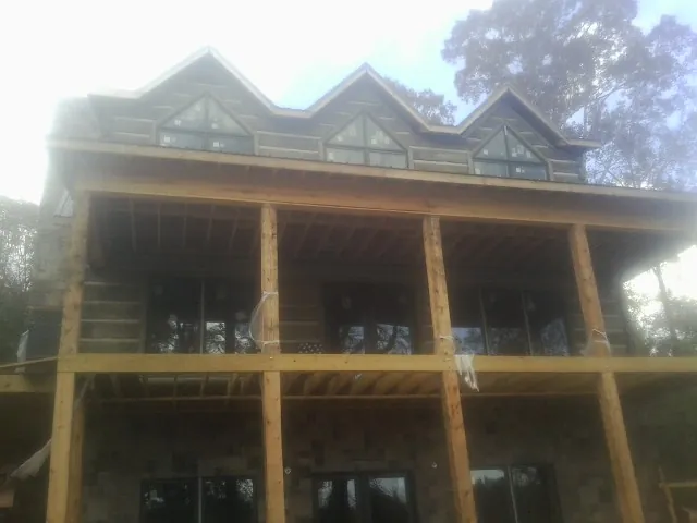 Dormers and porch framing on a large log home under construction — Roof Coating work by our crew in Firth