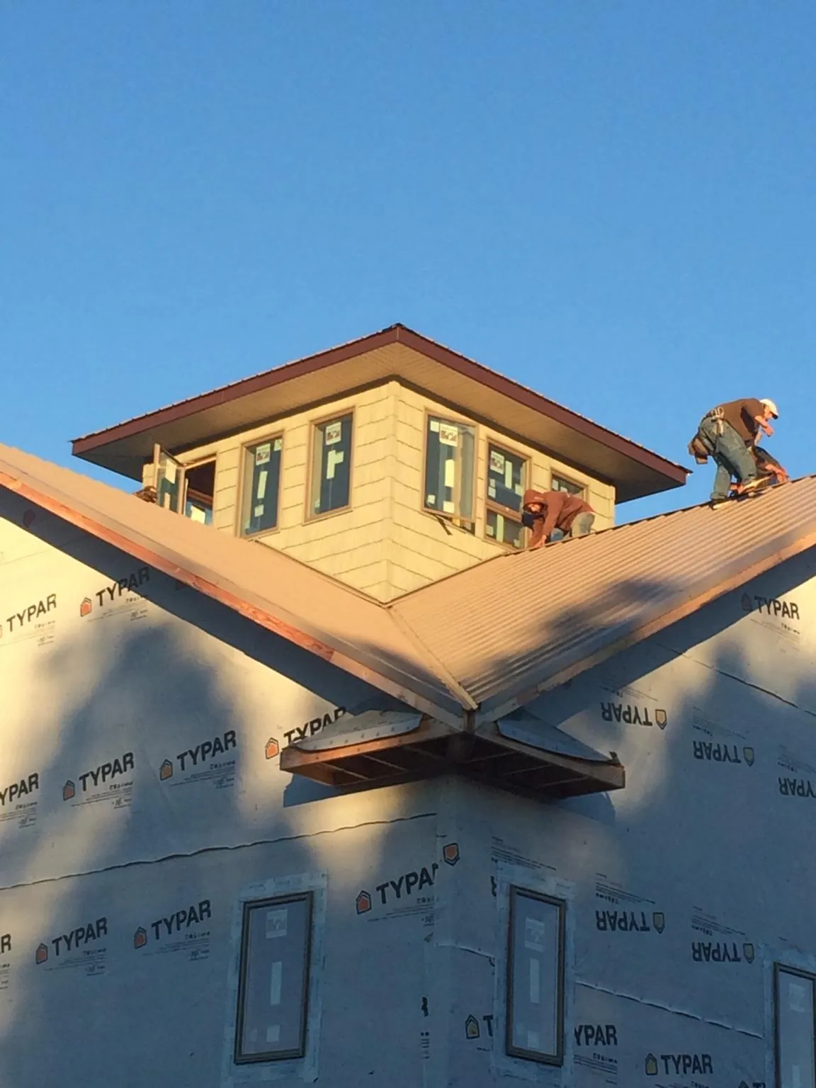 Roofers working around a rooftop cupola on a new metal roof at sunset — Roof Waterproofing in Firth by Roofing Brothers